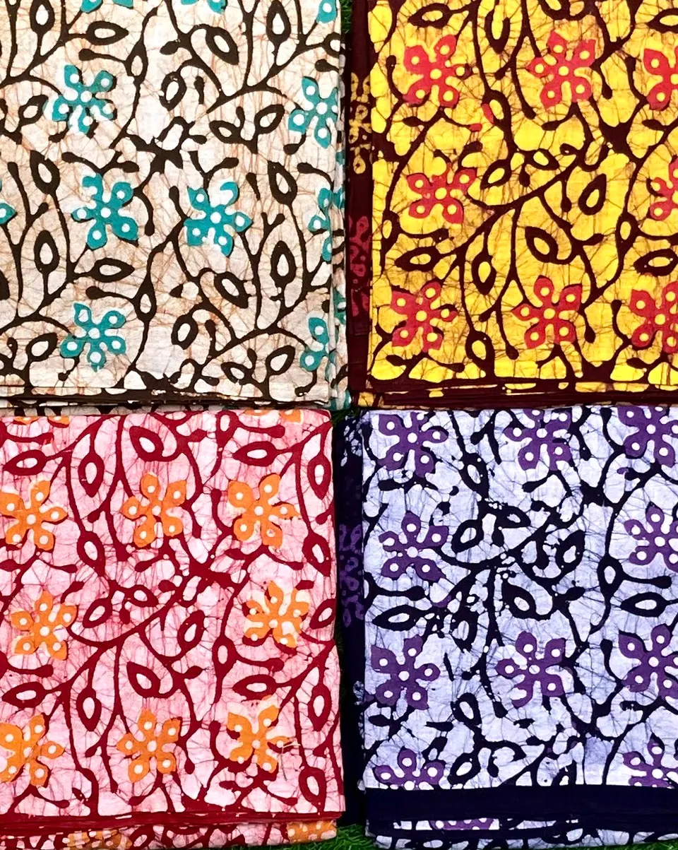 Four wax-resist printed cotton pieces in cream, yellow, pink and indigo with leaf and vine motifs